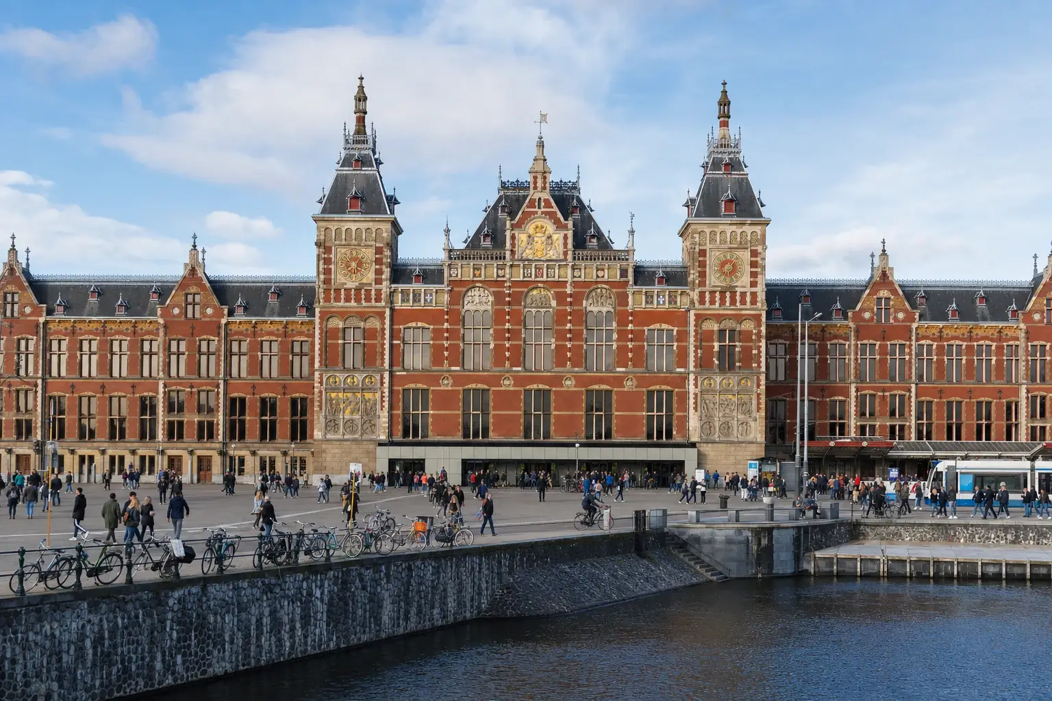 Red-brick facade and twin towers of Amsterdam Centraal railway station.