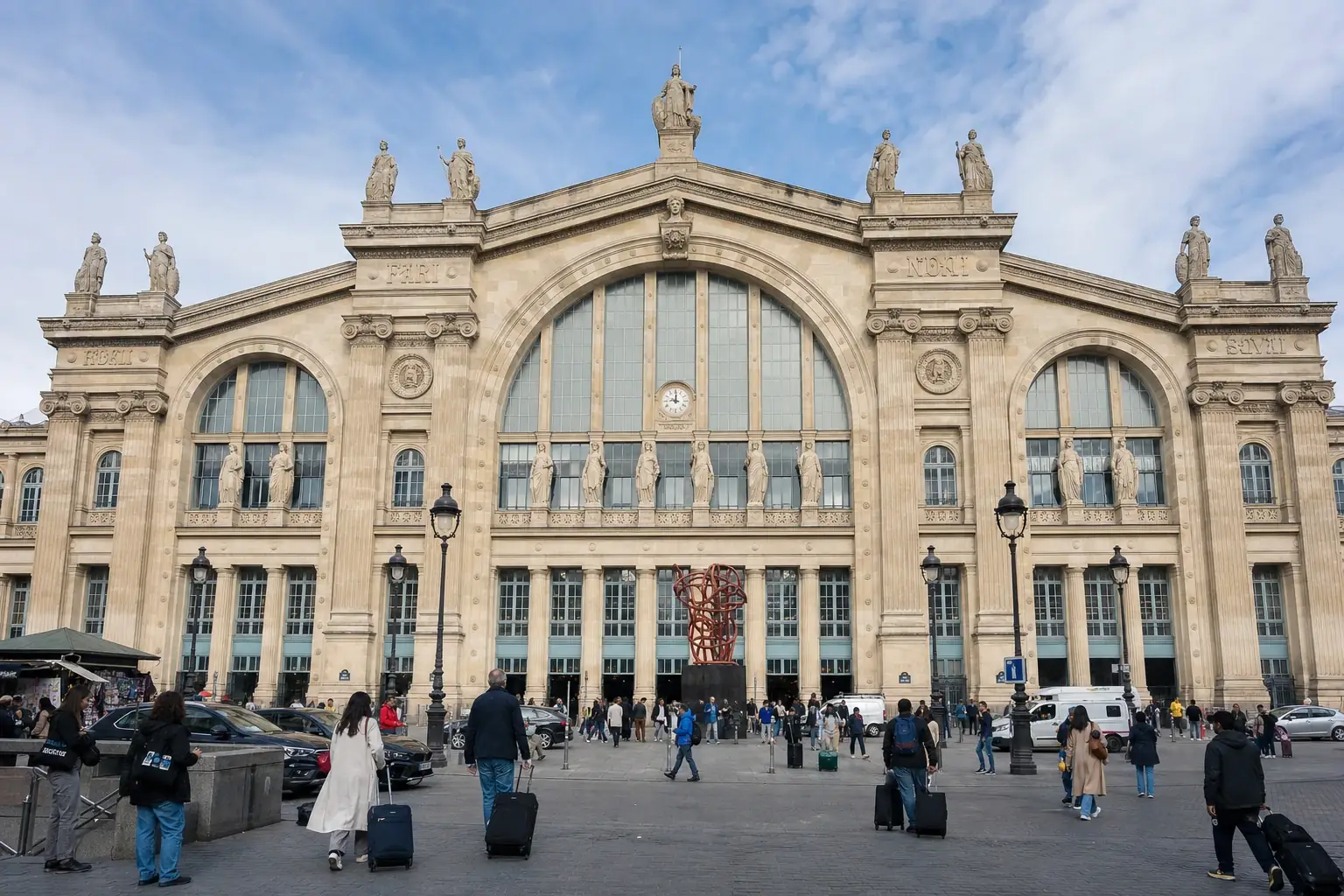 The neoclassical stone facade and forecourt of Paris Gare du Nord.