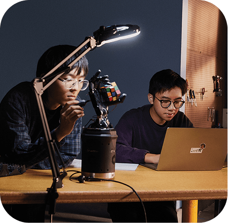 Two students working on a robotics project with a laptop