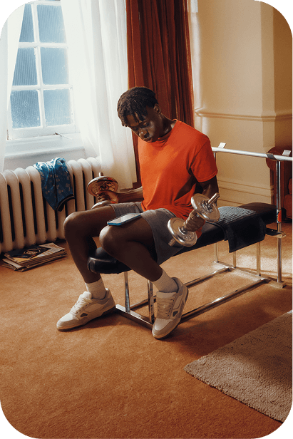 Teen sitting with a book and dumbbell in a room